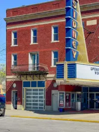 A Clopay VertiStack Clear door retrofitted into the brick facade of the historic Sidney Theatre, blending modern glass with classic architecture.