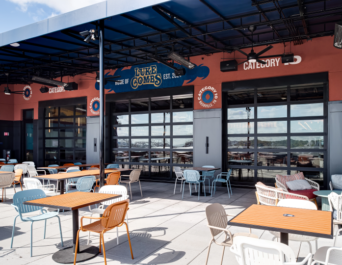 Clopay full-view glass garage doors installed at Luke Combs' Category 10 bar in Nashville, creating a seamless transition to the outdoor patio with modern seating.